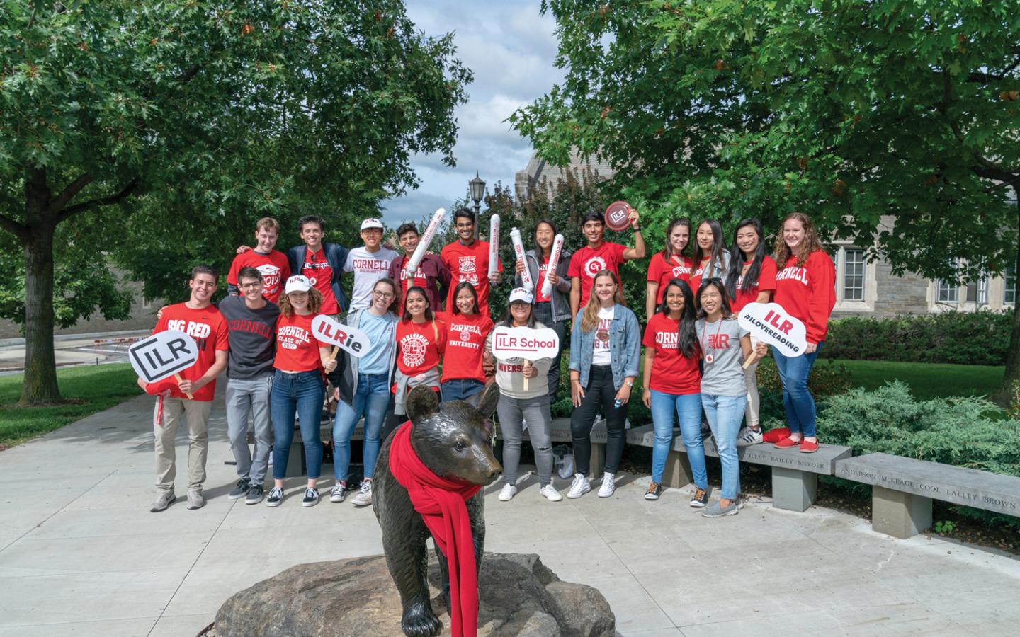 Large group of ILR students posing by Touchdown the Bear statue during Cornell Homecoming.