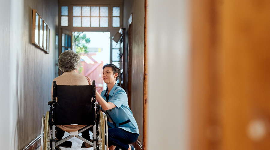 A nurse tends to a wheelchair bound patient in her home