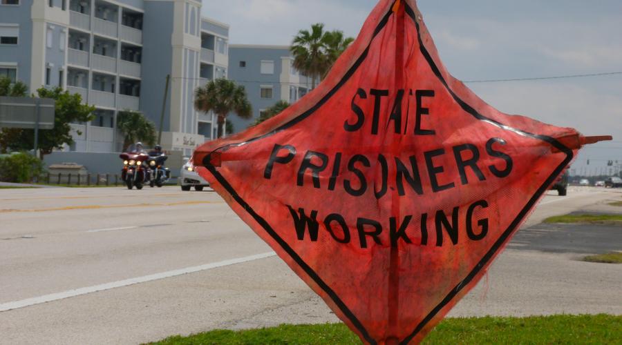 Sign by a road that says "State Prisoners Working"