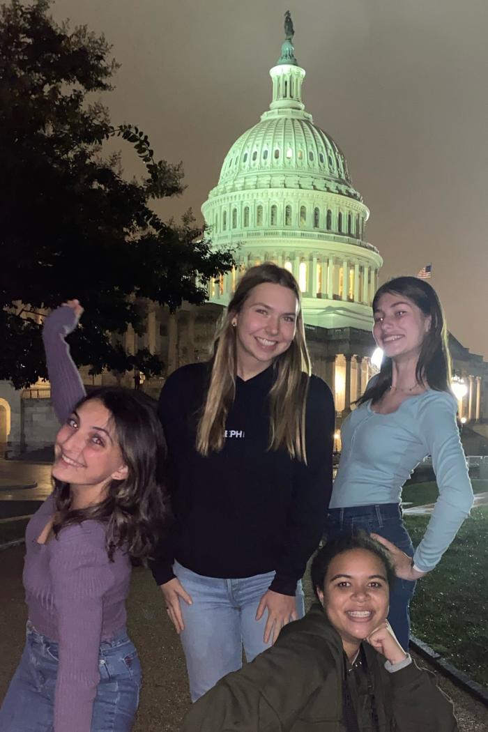 four students stand in front of the capitol