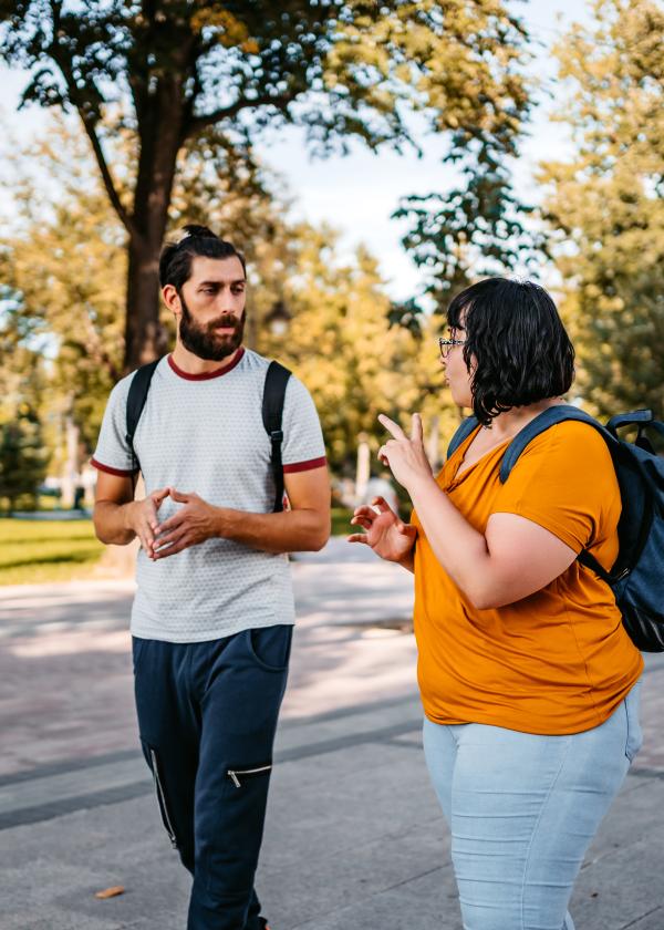 Twi friends walking outside using sign language to communicate